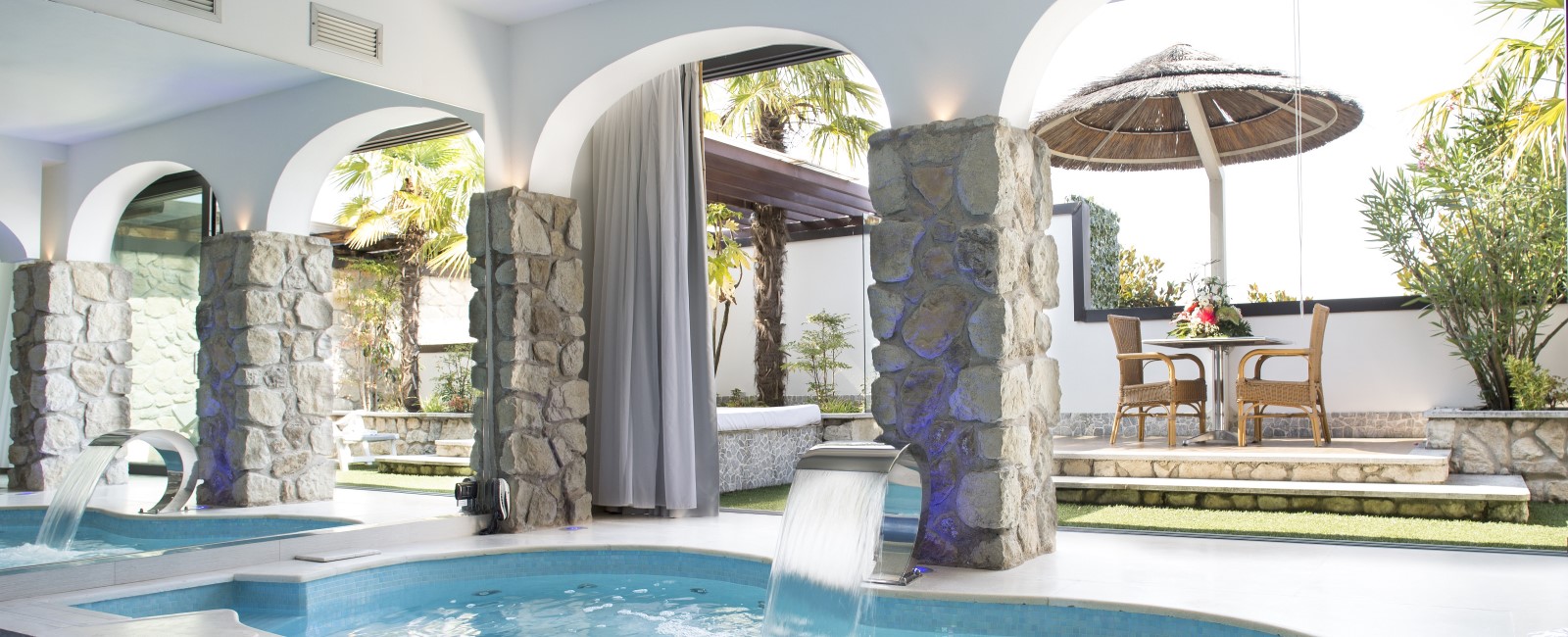 Motel K FantaSuite Antigua vista sul terrazzo esterno con gazebo e letto estivo, piscina idromassaggio con cascata, specchio di fianco alla piscina, camera a tema isole dei caraibi