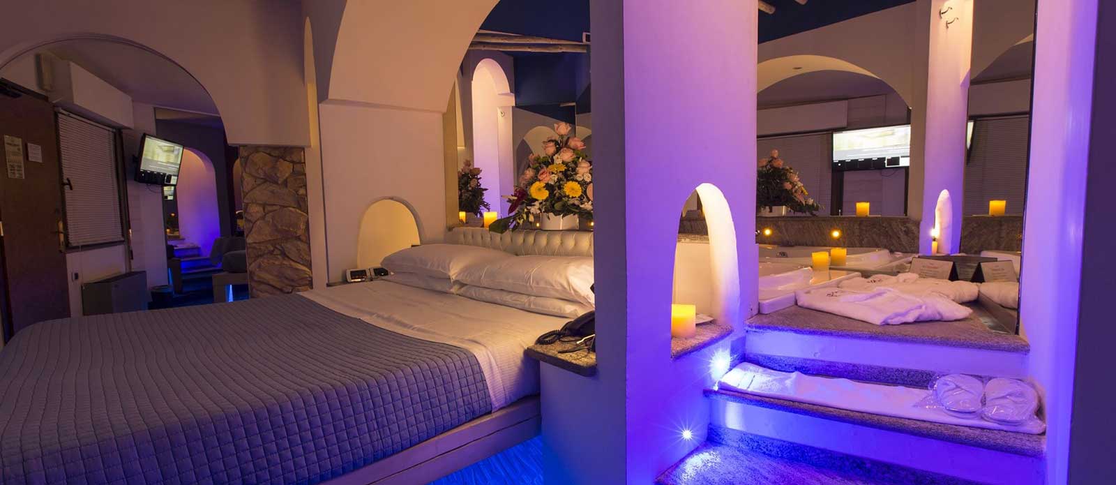 Motel K Junior Suite Santorini vista su letto matrimoniale con vasca idromassaggio dietro al letto , servizio candele in suite, camera a tema isole greche